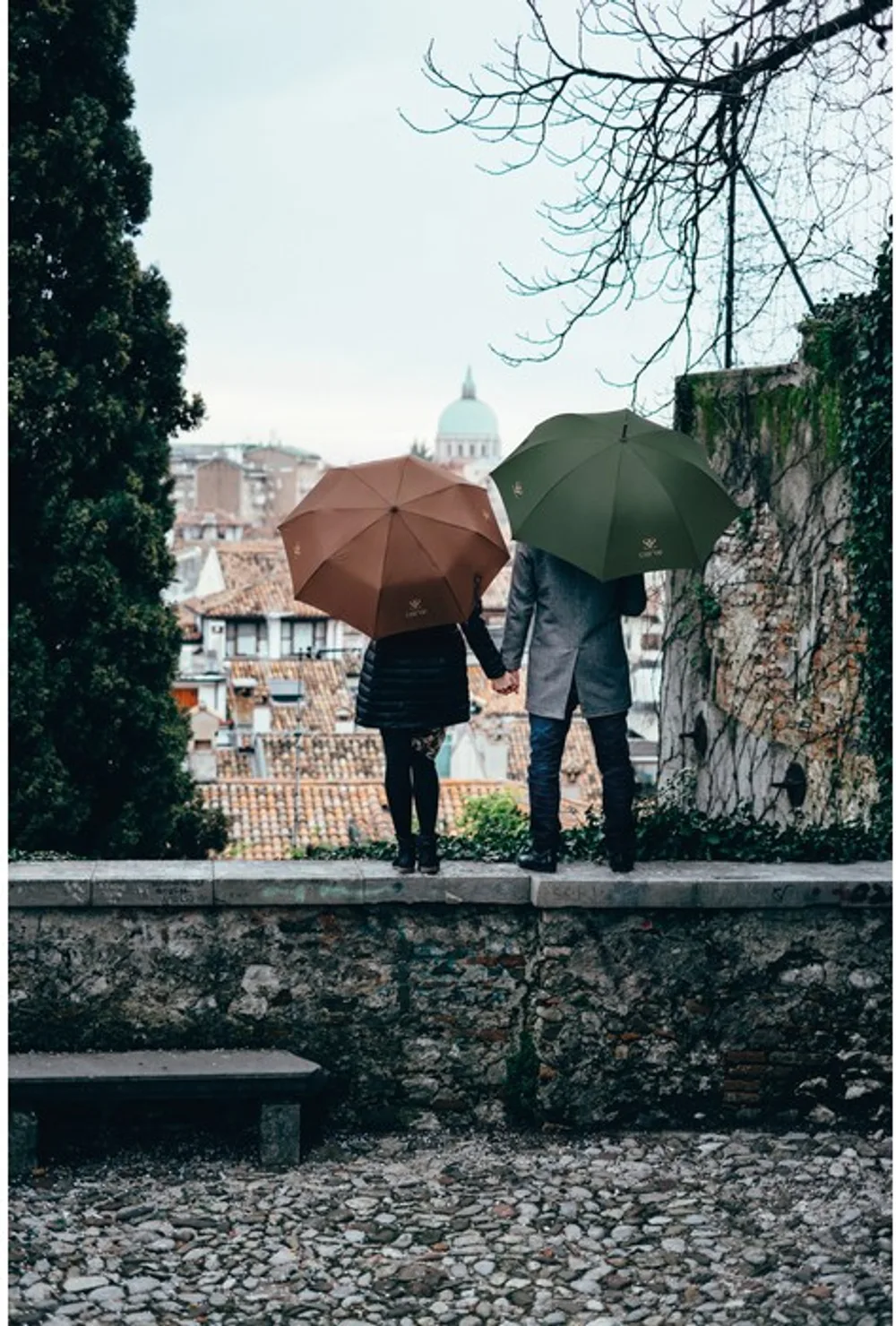 Paar mit zwei bedruckten Regenschirmen blickt über die Stadt